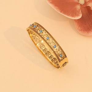 Vintage hollow gold stainless steel bangle with turquoise stone setting in studio light