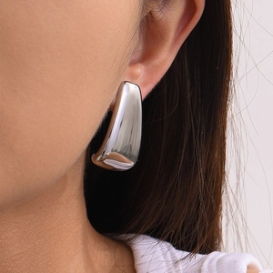 Boucles d'oreilles trapèze en acier inoxydable poli portées par un mannequin