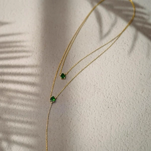Close-up of double-layer Y-necklace featuring teardrop emerald green stones in gold