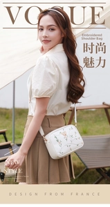 Detail shot of white leather camera bag with floral embroidery and 3D butterfly decor