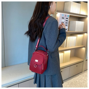 Detail of red nylon crossbody bag showing multiple zippered compartments and silver hardware