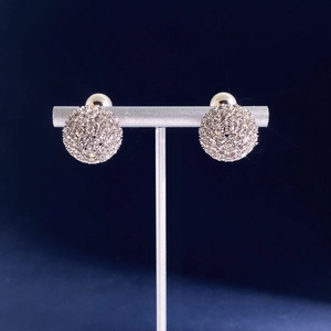 Macro detail of silver spherical stud earrings with crystals on a T-bar stand