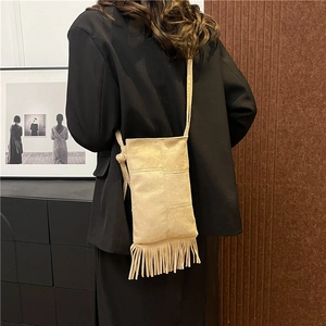 Chic beige tassel tote bag in soft suede finish shown as a crossbody on a model