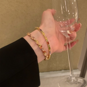 Dettaglio di bracciali in cristallo arcobaleno indossati tenendo un calice di vino