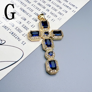 Macro shot of gold cross pendant with navy blue gemstones and sparkling zircon pavé