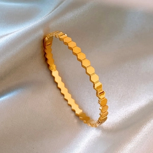 Golden honeycomb titanium steel bangle with a luxury hexagonal textured finish