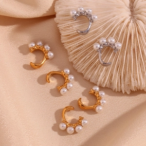 Gros plan de boucles d'oreilles C en or et argent avec perles sur de la soie