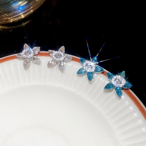 Close-up of zircon flower earrings in clear and sea blue crystals on a ceramic dish