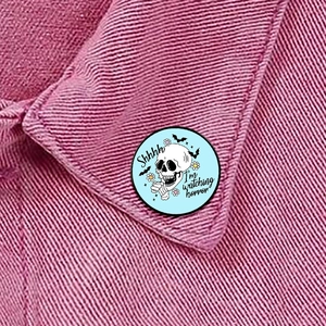 Close-up of Horror Movie Lover enamel pin with skull design on pink denim jacket collar