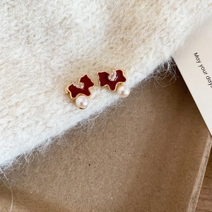 Detailed view of red butterfly earrings with white pearls on a soft knit fabric