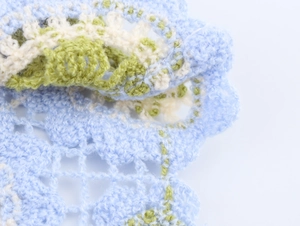 Gros plan de motifs au crochet faits main en bleu, blanc et vert avec textures fines