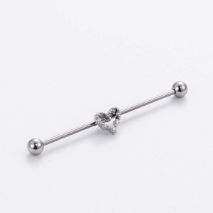 Detailed macro view of a silver heart-shaped industrial piercing with sparkling rhinestones