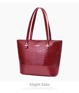 Detail view of red crocodile embossed tote bag with smooth texture and golden metal hooks