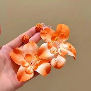 Vista detallada de los pendientes de flores de rafia naranja con pétalos de tela suave