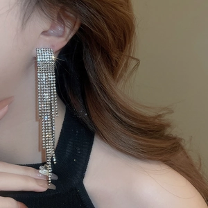 Close-up of elegant long tassel earrings with sparkling rhinestones worn by a model