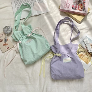 Detail of mint green and lavender drawstring canvas tote bags with contrast satin ribbons