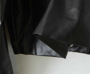 Close-up of black PU leather motorcycle jacket showing detailed lychee grain texture