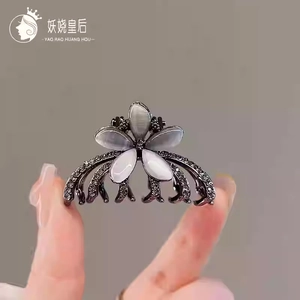 Close-up of crystal flower hair claw with opal petals and rhinestones on gunmetal alloy