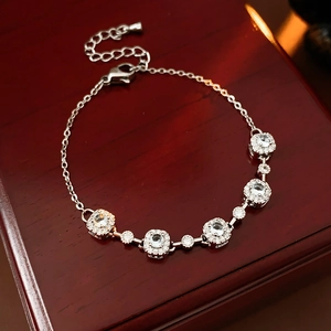 Détail d'un bracelet en argent avec zircons géométriques sur un support en bois