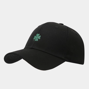 Close-up of green four-leaf clover embroidery on a black cotton baseball cap