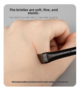 Detail of angled blade eyeliner brush drawing a precise line on skin for makeup