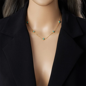 Minimalist gold chain necklace with turquoise beads on model neck in dark setting