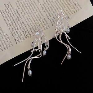 Macro shot of silver-tone irregular branch earrings with dangling white pearls