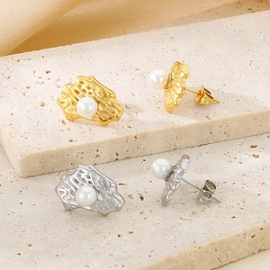 Detail showing gold and silver irregular textured earrings with inlaid pearls on stone