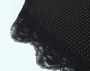 Detailopname van zwarte polkadots stof met fijne kantafwerking op deze casual damestop