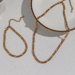 18K gold plated stainless steel Figaro chain necklaces set on decorative white plate