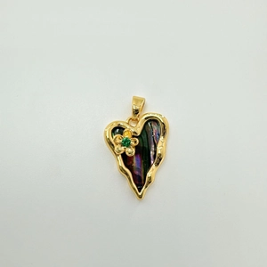 Macro detail of heart-shaped shell pendant with gold flower and green gemstone inlay