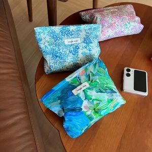 Three floral Liberty print cosmetic bags with simple wish labels on a wooden table