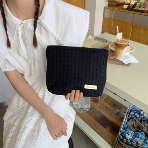 Close-up of black waffle textured cosmetic pouch with a small woven brand label