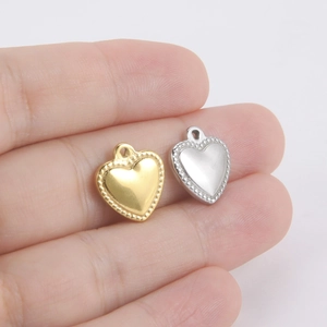 18K gold and silver heart charms with beaded edges on a palm for size scale