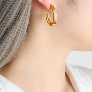 Elegant gold U-shaped pearl earrings on a model, featuring minimalist French style design