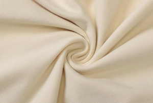 Detailed macro shot of the cream-colored knitted fabric texture for a maxi dress