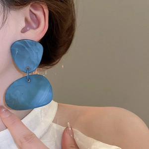 Detailed close-up of blue marble acrylic geometric drop earrings worn by a model