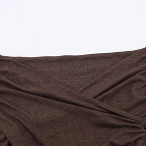Detailed close-up of dark brown knitted fabric with elegant criss-cross pleated collar