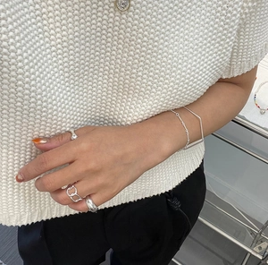 Close-up of minimalist S925 sterling silver twist rings and bracelet on model