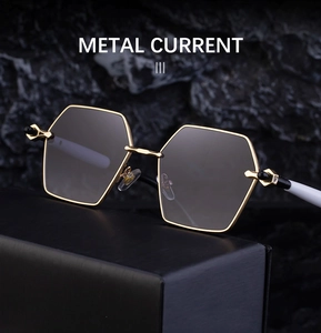 Detailed close-up of metallic hexagonal sunglasses with grey lenses on a dark stone base