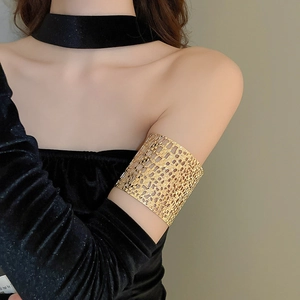 Detailed view of a wide gold openwork armlet featuring a geometric lattice pattern