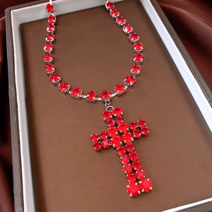 Close-up of gothic cross pendant necklace with red rhinestones in a luxury jewelry box