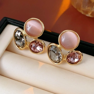 Macro detail of vintage gold earrings featuring pink cat eye stone and faceted crystals