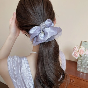 Close-up of a purple organza bow scrunchie with pearls styled on a woman's hair