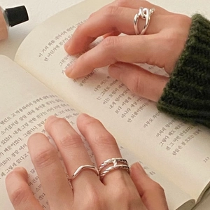 Detail of double-layer silver rings with H-shape and chain design worn on fingers