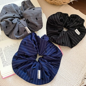 Détails du tissu rayé des chouchous avec de petits nœuds brodés et une étiquette tissée