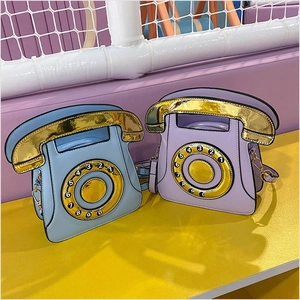 Detail of retro telephone shaped crossbody bags in light blue and purple with gold dials