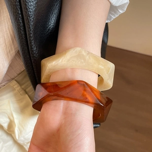 Detail of irregular resin bangles with marble texture and amber brown finish