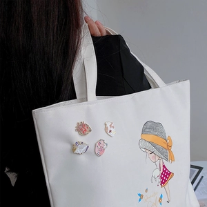 Detailed view of colorful anatomical heart enamel pins on a white canvas tote bag