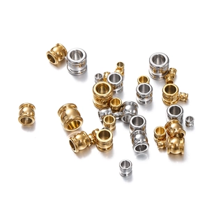 Macro shot of polished gold and silver cylindrical stainless steel DIY beads on white background